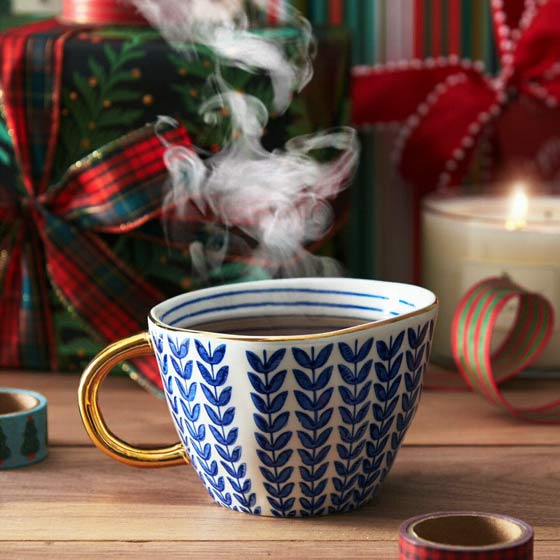 Steaming cup of tea in a beautiful mug with a holiday background